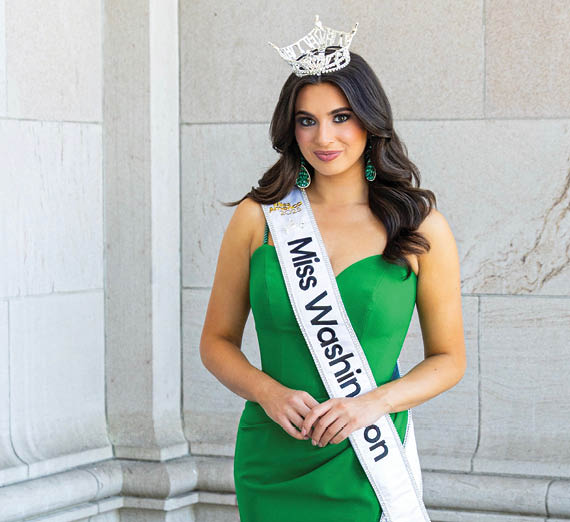 A woman stands with her arms crossed next to a window